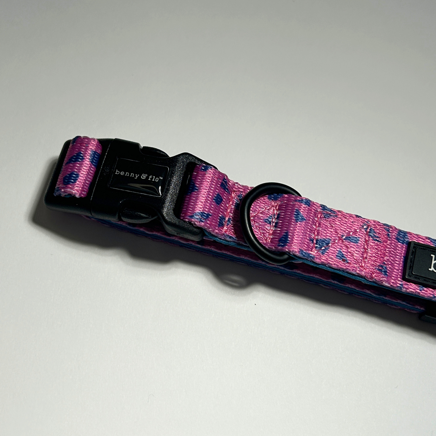 Pink and blue patterned dog collar with black hardware on a white background