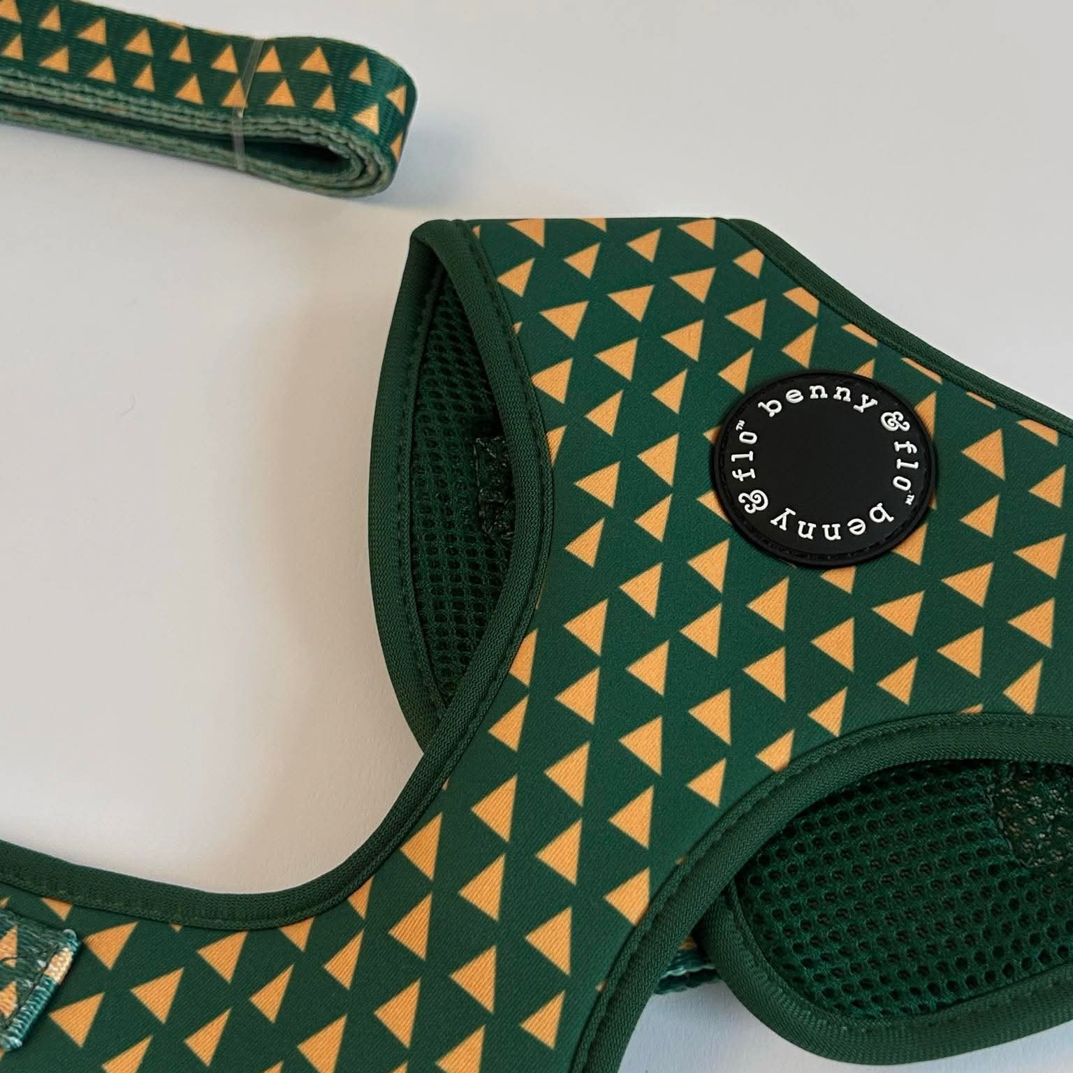 Green and yellow patterned dog harness with brand logo on a white background