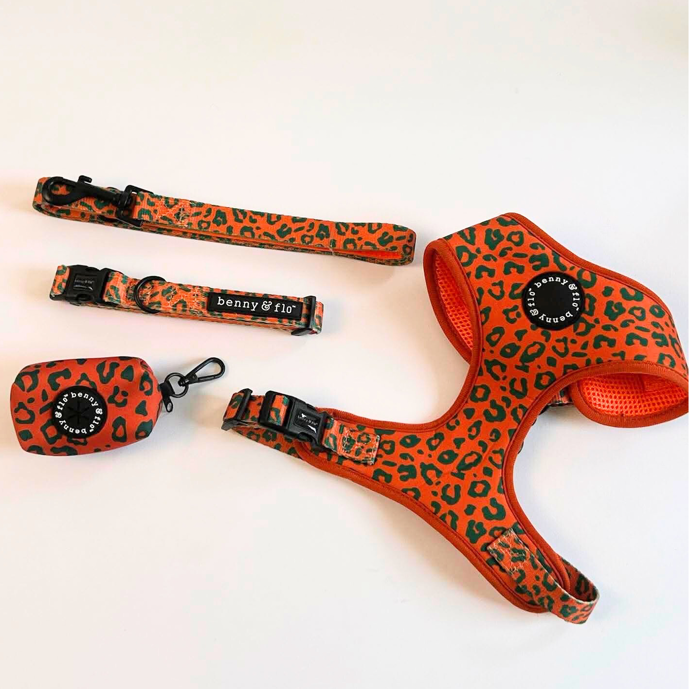Orange and green leopard print dog harness, collar, and leash set on a white background