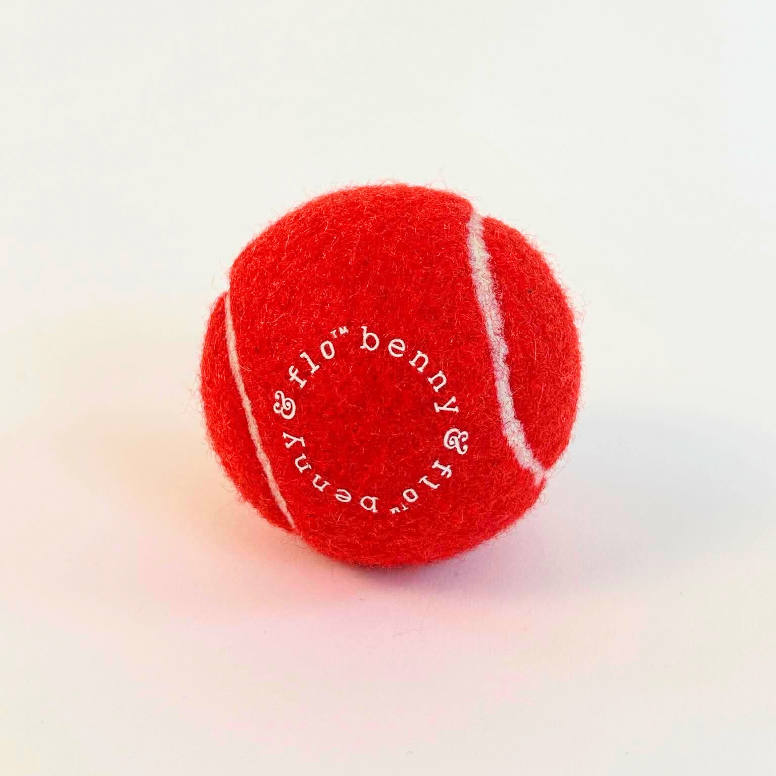 Red tennis ball with white text on a white background